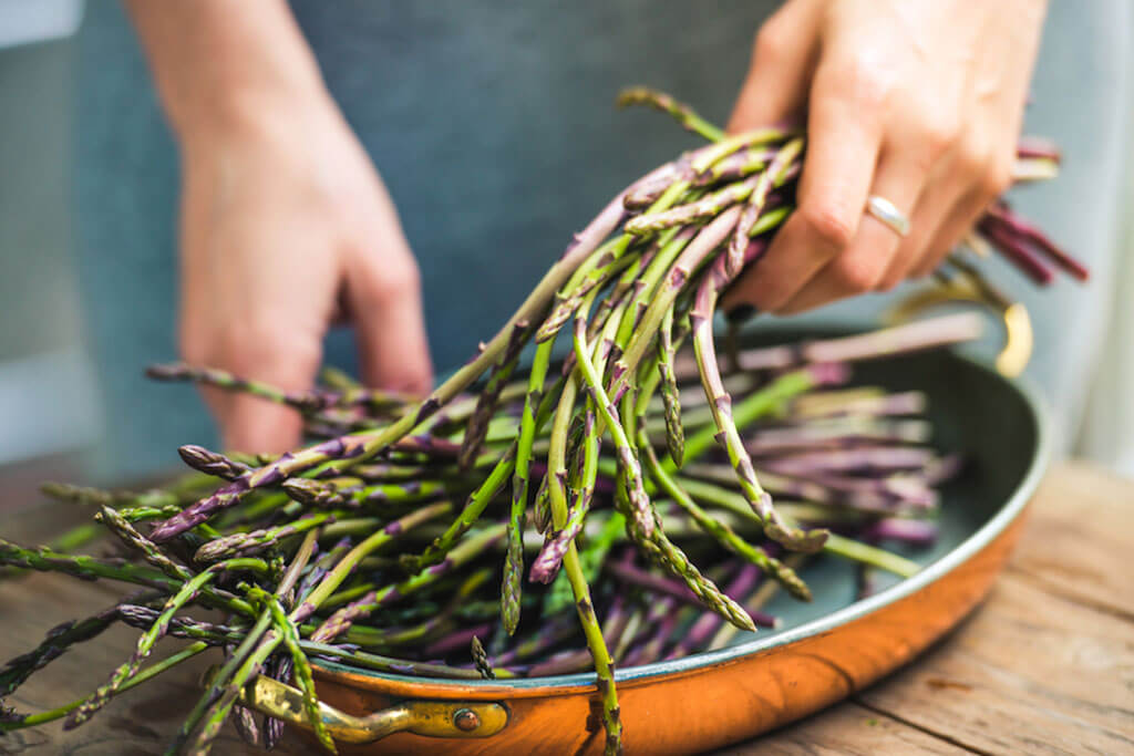 Woman putting asparagus in pan