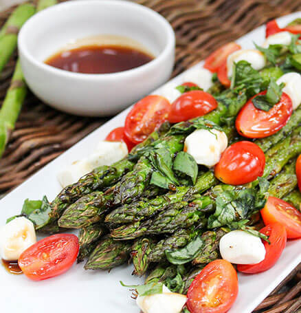 Freshly-grilled asparagus and brilliant white caprese cheese top a salad.