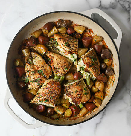 A close-up show of a plate of asparagus stuffed chicken, potatoes, and seasoning.