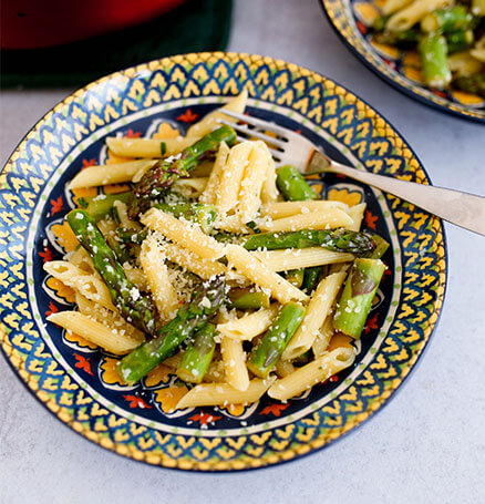 A brightly-colored bown of lemon asparagus pasta dusted with parmesean cheese.
